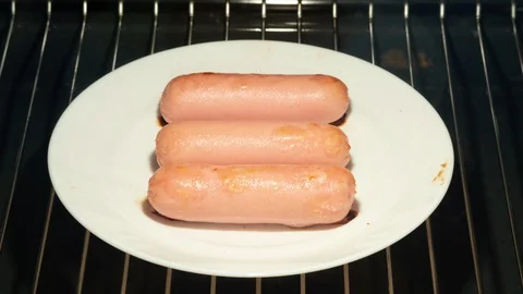 Cooking of roasted pork, beef or chicken sausages on white plate in oven Video stock 129832866
