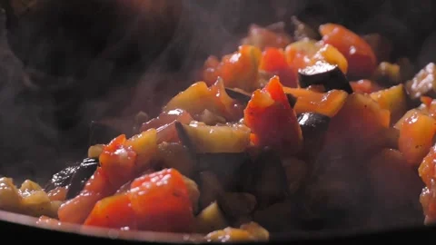 Cooking roasted vegetables. Chef stirs with spoon into steaming hot pan Vidéo 250594751