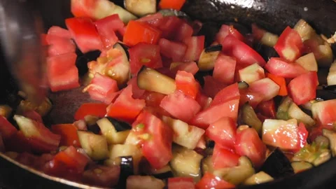 Cooking roasted vegetables. Chef stirs with spoon into steaming hot pan Stock Footage 250774156