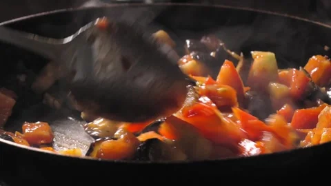 Cooking roasted vegetables. Chef stirs with spoon into steaming hot pan Vidéo 250777985