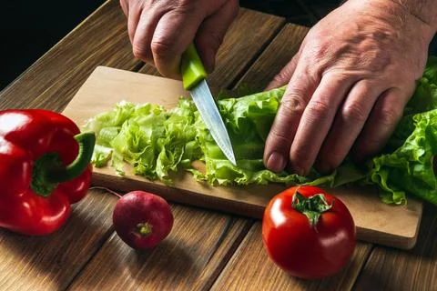 Cooking salad in the restaurant kitchen. Chef is hands close-up cut salad Stock Photos