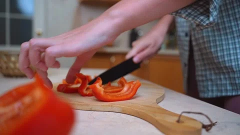 Cooking scene showcasing peppers being cut on wooden surface 库存影片 328494658
