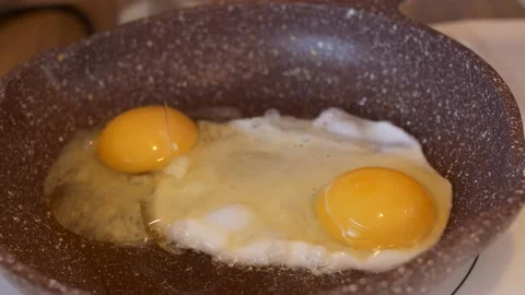 Cooking scrambled eggs for breakfast, another egg is driven into pan for fried Stock Footage 220340884