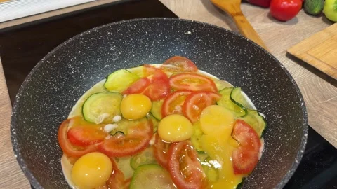Cooking a scrambled eggs with peppers, tomatoes Stock Footage 303977588