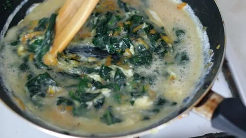 Cooking scrambled eggs with spinach in frying pan healthy breakfast Stock Footage 242057555