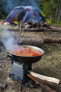 Cooking scrambled eggs with vegetables on the fire in the woods Stock Photos