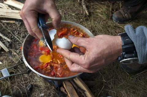 Cooking scrambled eggs with vegetables on the fire in the woods Stock Photos