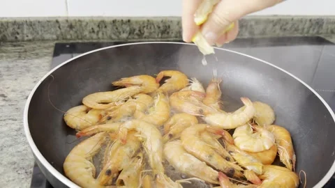 Cooking seafood. Adding lemon juice when frying shrimp for a culinary blog Stock Footage 330943922