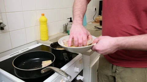 Cooking sequence: man prepares breaded dish on stove in home kitchen Stock Footage 307447611