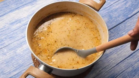 Cooking a simple soup in a kitchen with a blue table Stock Footage 340179214