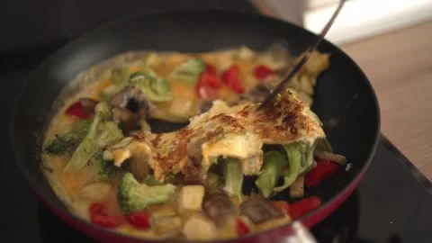 Cooking a simple vegetable dish on the stove with eggs and cheese at home in the Stock Footage 337106406