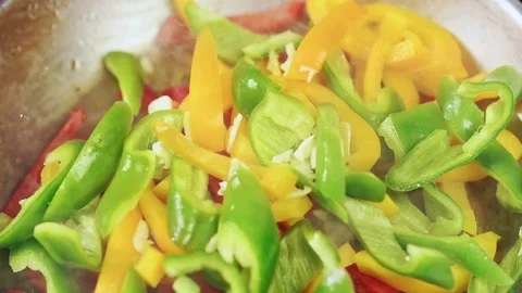 Cooking of sliced peppers in a frying pan.Adding of chopped garlic. Stock Footage 151045203