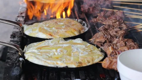 Cooking sliced potatoes mixed with eggs and meat on grill or skewed kebab Stock Footage 161255618