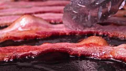 Cooking slices of bacon for breakfast. Bacon Frying in a Pan. 스톡 동영상 334641764