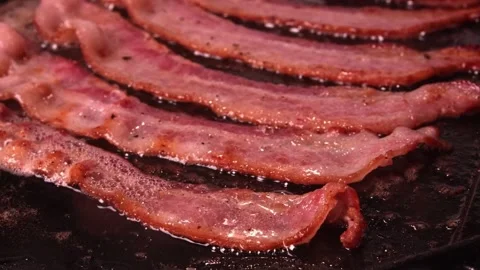 Cooking slices of bacon for breakfast. Bacon Frying in a Pan. 스톡 동영상 334641768
