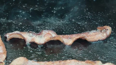 Cooking slices of bacon outside on a griddle Video stock 284777281
