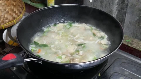 Cooking soup in a black pan with boiling water Stock Footage 307558074