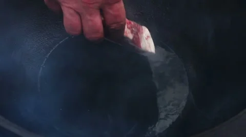 Cooking soup from lamb. Man putting chopped pieces of mutton in cauldron. Stock-Footage 63662420