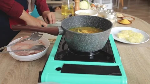 Cooking soup on stove while cutting vegetables on board with ingredients nearby Stock Footage 343729788