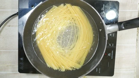 Cooking  spaghetti with boiled bubble fresh water and smoke in induction pan  Stock Footage 130097405