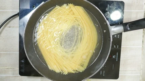 Cooking  spaghetti with boiled bubble fresh water and smoke in induction pan  Stock Footage 130100345