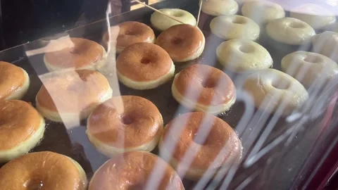 Cooking staff flipping donuts in deep fryer oil Stock Footage 346569414