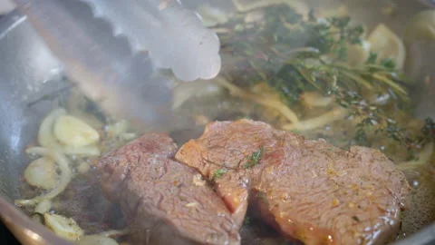 Cooking steak in cast iron pan in the kitchen at home. Slow motion video. Stock Footage 233619061
