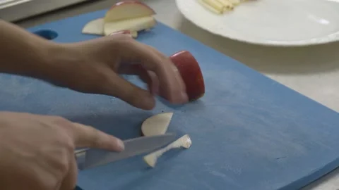 Cooking student cutting apple on blue board Stock Footage 229190912