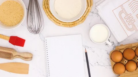 Cooking supplies appear on marble table and notebook for recipe - Stop motion Stock-Footage 128577173