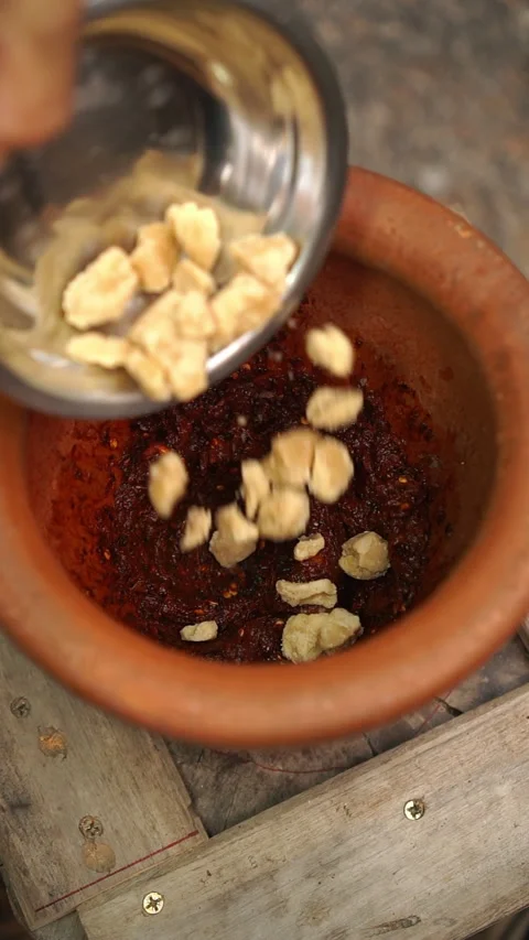 Cooking Thai food: pounding roasted dried chilies, garlic, shallots, and green m Stock-Footage 346164480