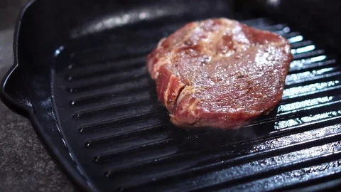 Cooking thick piece of raw beef meat steak on hot oily grill frying pan in close Stock Footage 105895094