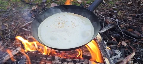 Cooking tin pancakes for on a burning campfire. Stock Footage 246575720