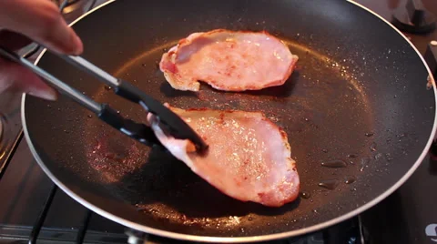 Cooking two bacon rashers in a frying pan Stock Footage 36146863