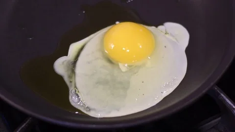 Cooking two eggs over a residential kitchen stove, shot 1 of 2 스톡 동영상 82585409
