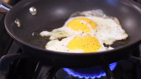 Cooking two eggs over a residential kitchen stove Video stock 82585980
