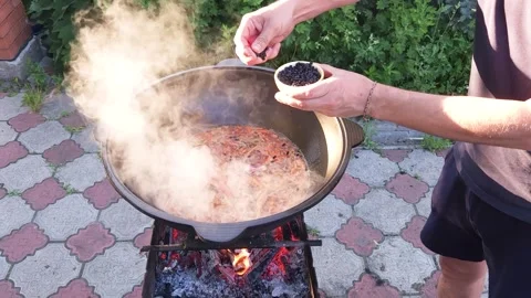 Cooking Uzbek pilaf. Adding barberry to boiling zirvak Stock Footage 244484710