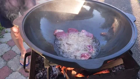 Cooking Uzbek pilaf. Adding fresh meat to hot vegetable oil for frying Stock Footage 244484670
