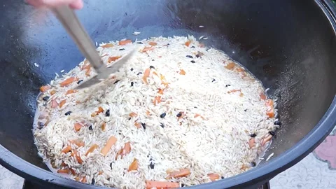Cooking Uzbek pilaf. We form a hill of rice and cover with a bowl for steaming Stock Footage 244484657