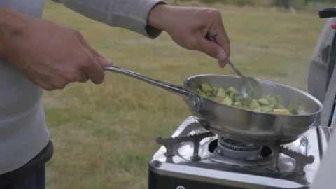 Cooking vegetables in the back of a van during a roadtrip, in New Zealand Stock Footage 219895220