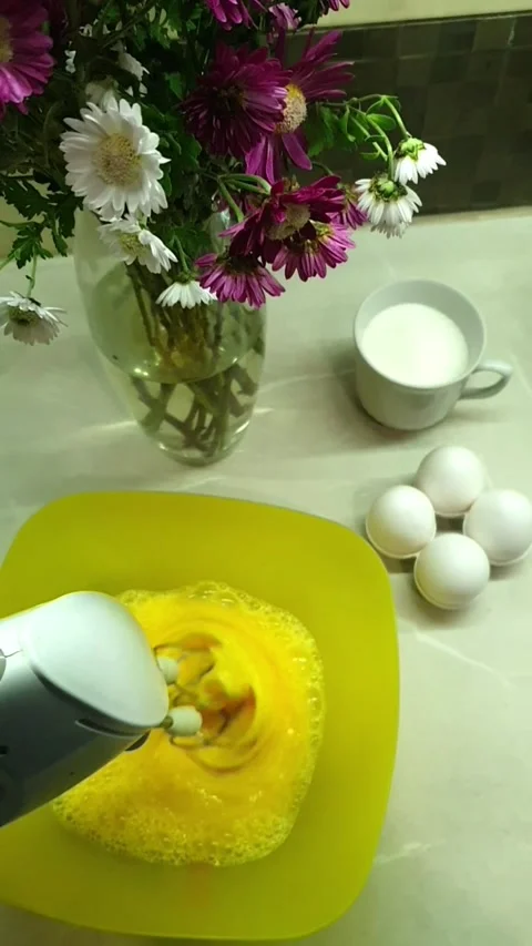 Cooking Whisking Eggs for Dessert on Table with Flowers Stock Footage 296076510