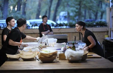 Cooks communicating while preparing fast food meals in a kitchen of a restaur Stock Photos