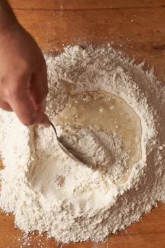 Cook's hand holds a spoon while stirring wheat flour preparation Stock Photos