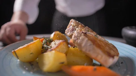 Cooks hand puts a fresh fried steak on white plate and maiking final decoration Video stock 127056913