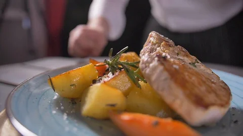 Cooks hand puts a fresh fried steak on white plate and maiking final decoration Stock Footage 127062037