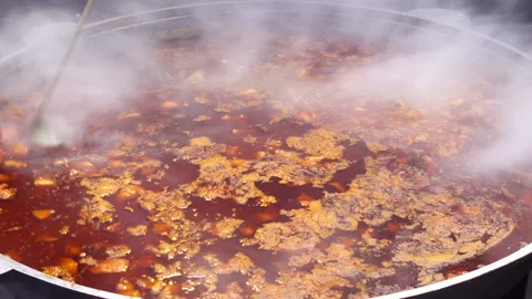 Cook's hand stirring vegetable soup. Street food large cauldron with hot soup. Stock Footage 101479387