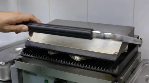 Cook's hands are taking off falafels from the iron grill Stock Footage 73458942