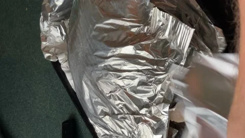 The cook's hands are wrapping the chicken in foil for roasting in the oven Stock Footage 234724054