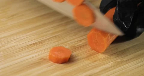 Cook's hands in black gloves cutting fresh carrot into slices on wooden board. Vídeos de archivo 147347650