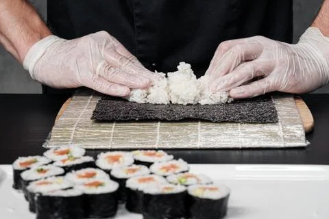 Cook's hands close-up. The chef makes sushi and rolls from rice. White gloves. Stock Photos