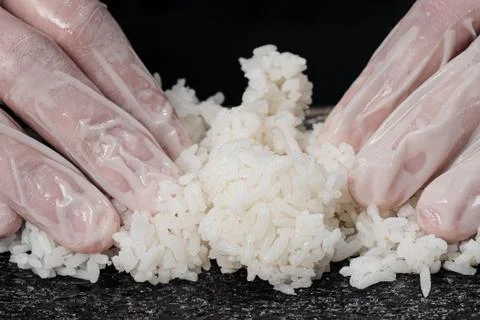 Cook's hands close-up. The chef makes sushi and rolls from rice. White gloves. Stock Photos